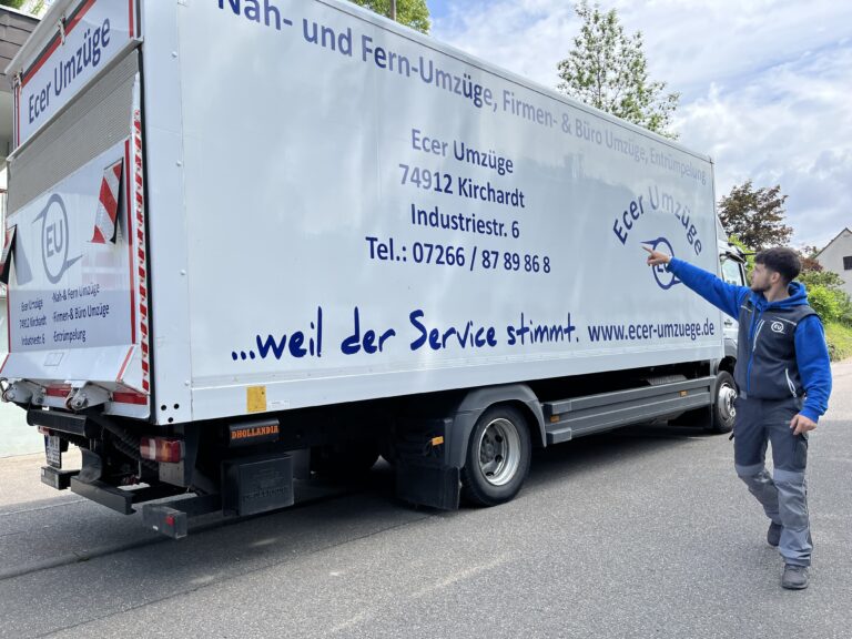 Seitenansicht eines Ecer-Umzüge-LKW mit gut sichtbarer Firmenaufschrift, Kontaktdaten und dem Slogan „…weil der Service stimmt“, rechts zeigt ein Mitarbeiterarm auf das Firmenlogo.