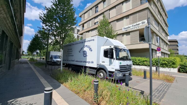 Zwei LKW von Ecer Umzüge in einer Straße.