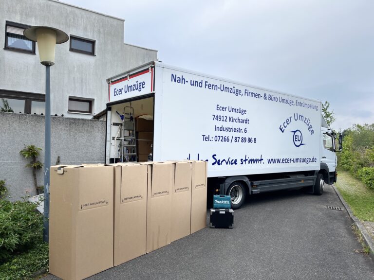 Umzugs-LKW von Ecer Umzüge vor einem Wohnhaus, davor ordentlich aufgereihte Umzugskartons und Umzugsequipment.